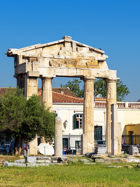 Ancient Greek columns at Roman Agora, Athens with surrounding buildings.