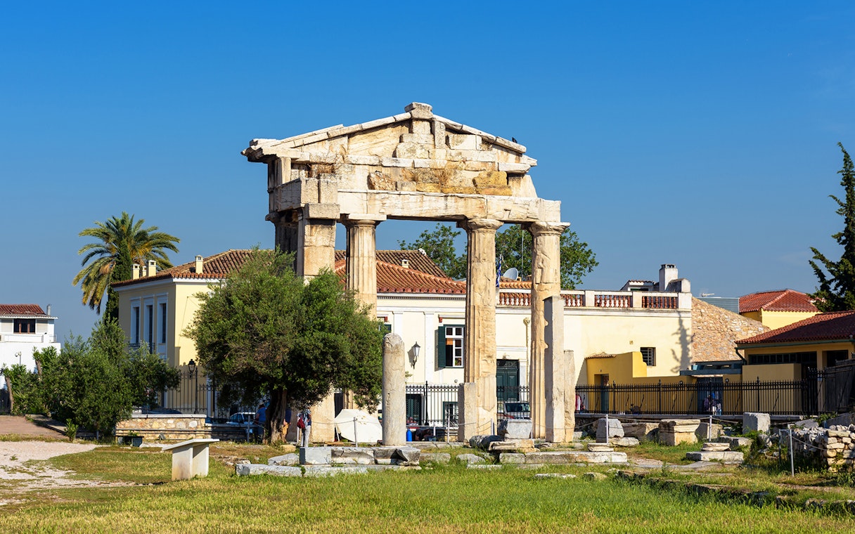 Ancient Greek columns at Roman Agora, Athens with surrounding buildings.