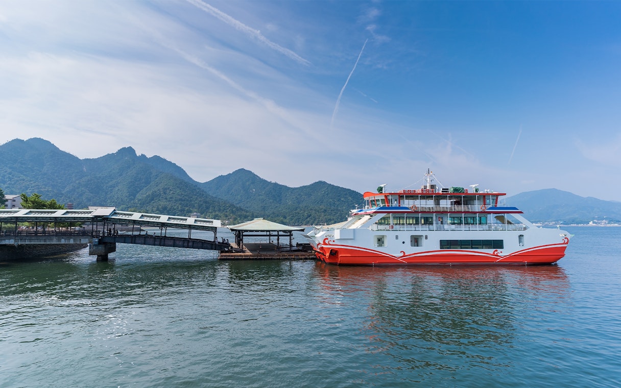 JR West Miyajima ferry docked with mountains in the background.
