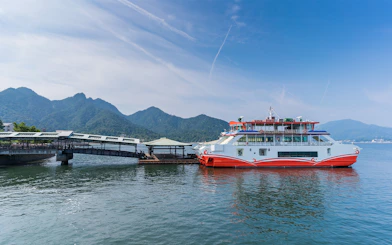 JR West Miyajima ferry docked with mountains in the background.