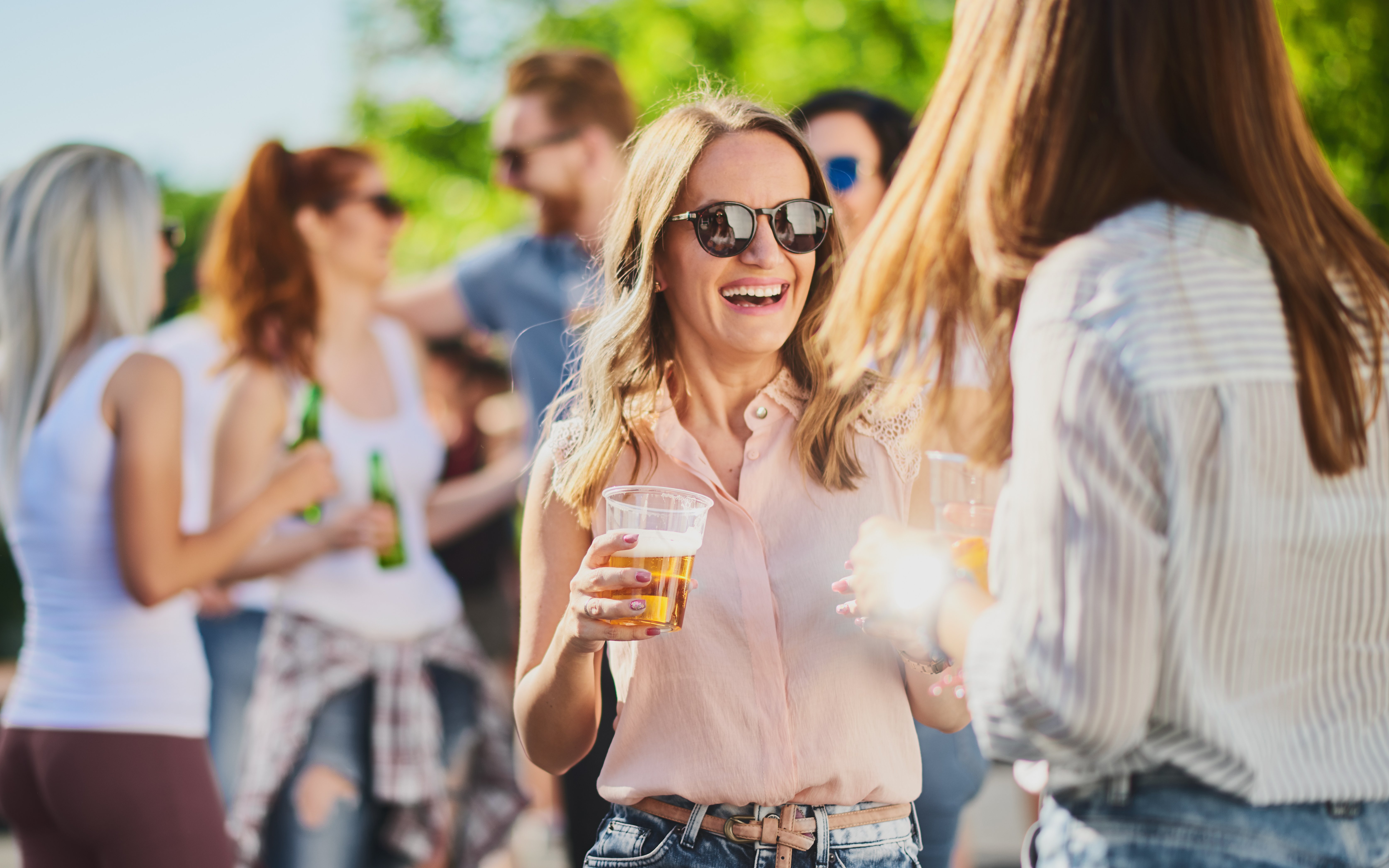Group of people standing, drinking an having a good time at outdoor party