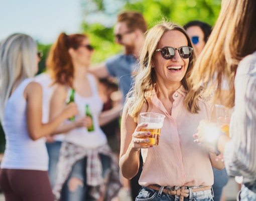 Group of people standing, drinking an having a good time at outdoor party