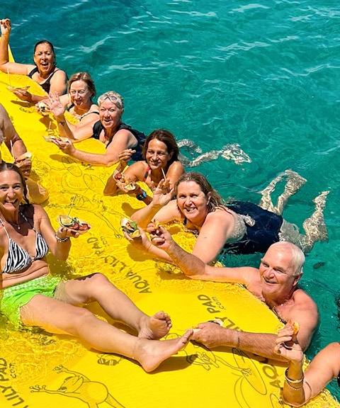 Group enjoying seafood on a floating mat during Rottnest Island Luxe Seafood Cruise.