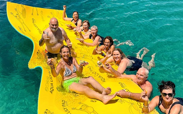 Group enjoying seafood on a floating mat during Rottnest Island Luxe Seafood Cruise.