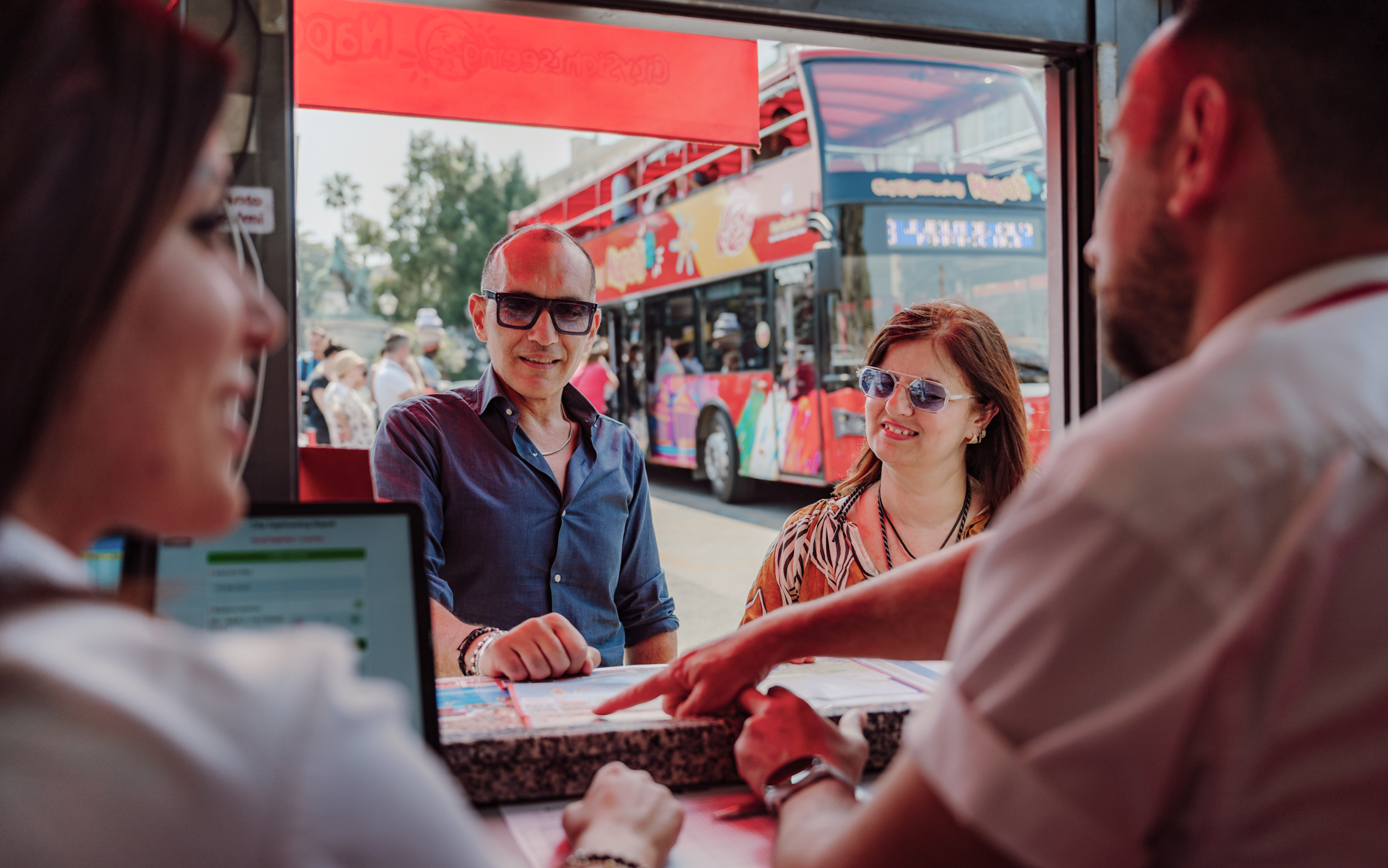 Tourists at a ticket counter for the City Sightseeing Naples Hop-on Hop-off Bus Tour.