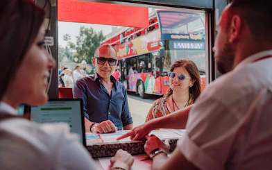 Tourists at a ticket counter for the City Sightseeing Naples Hop-on Hop-off Bus Tour.