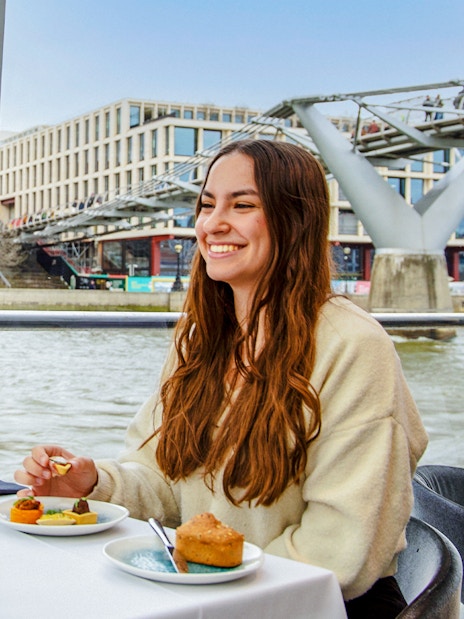Dinner cruise on the Thames River with view of Millennium Bridge and St. Paul's Cathedral.