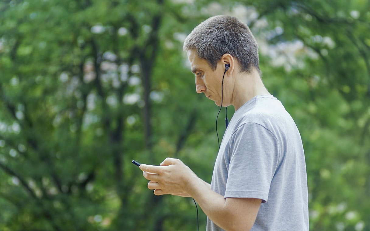 Guest using audio guide in a park setting.