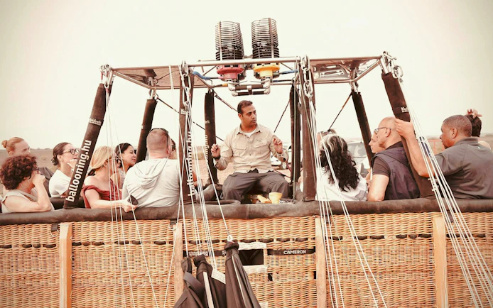 Hot air balloon passengers and pilot preparing for sunrise flight in Marrakech.