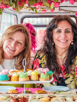 Guests enjoying afternoon tea on a vintage double-decker bus in London.