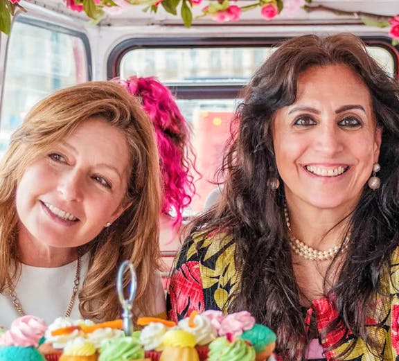 Guests enjoying afternoon tea on a vintage double-decker bus in London.