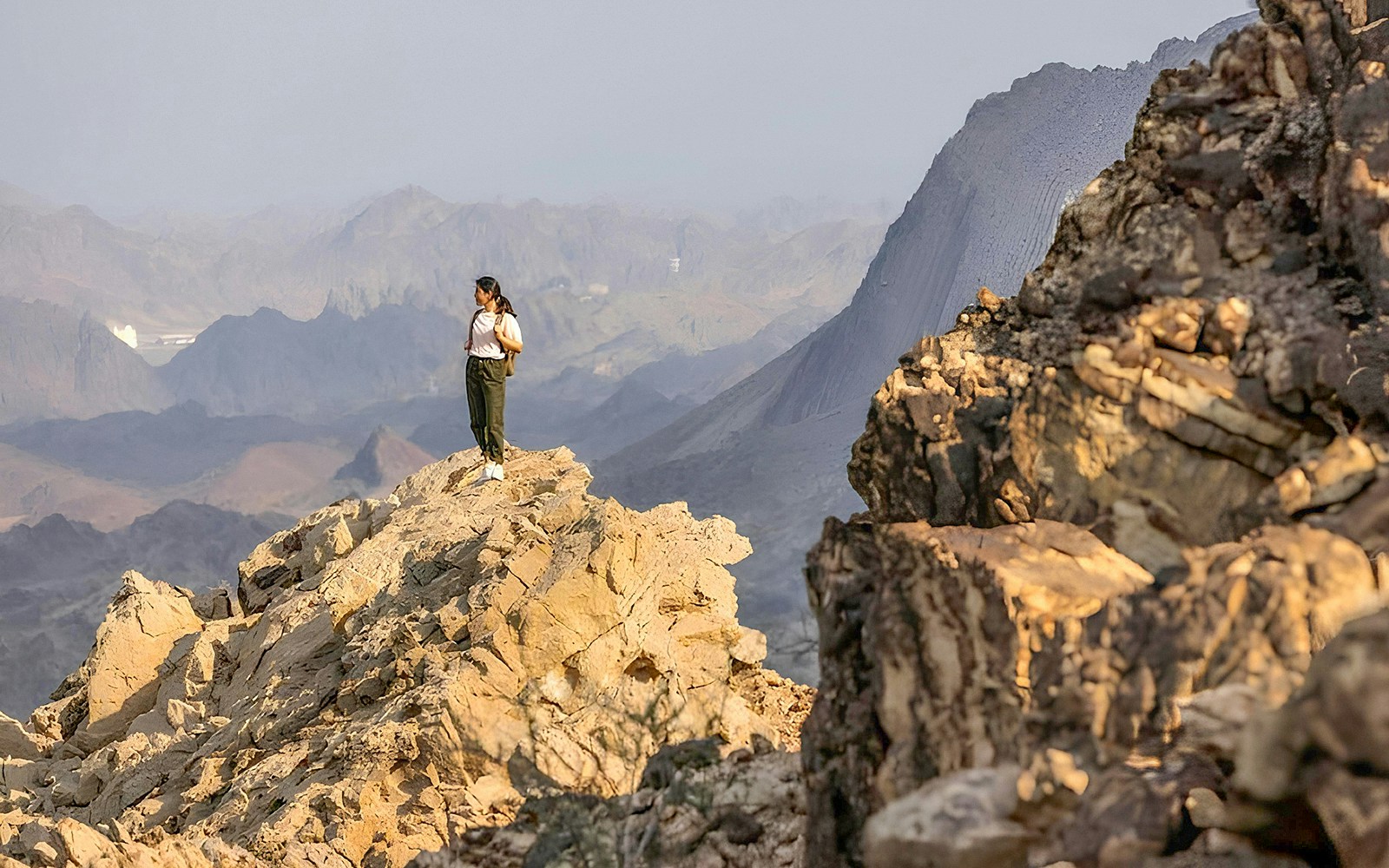 A woman standing on top of the mountain hiking