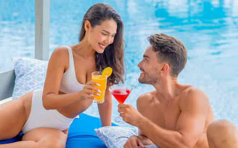 Couple enjoying drinks by the pool at Flamingo Beach Club.