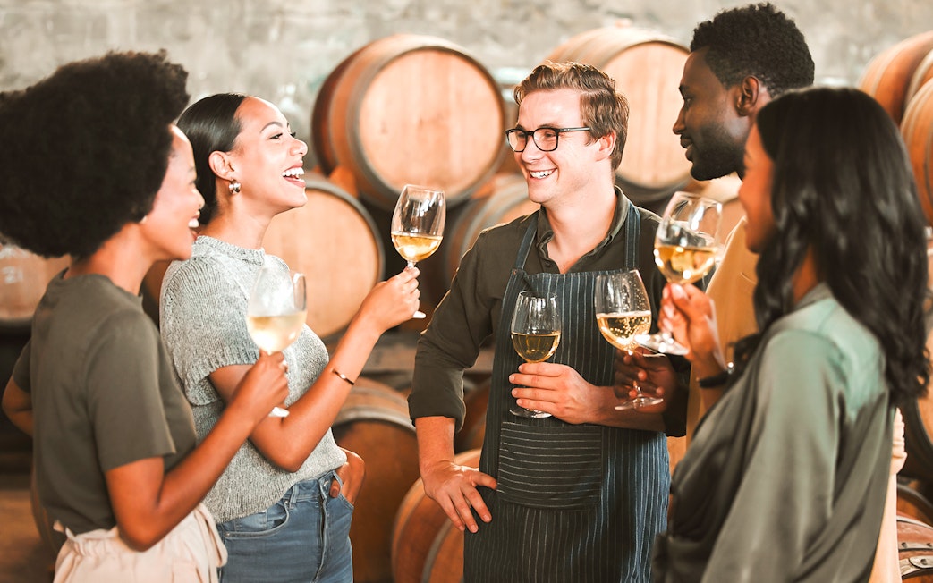 Visitors enjoying wine tasting at Cálem Cellars, Porto, with barrels in the background.