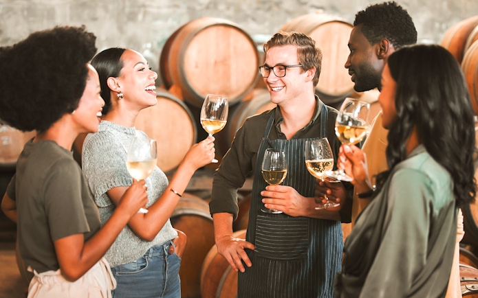 Visitors enjoying wine tasting at Cálem Cellars, Porto, with barrels in the background.