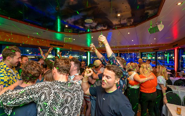 Partygoers dancing and celebrating on a boat during Hamburg's Friday and Saturday night boat party.