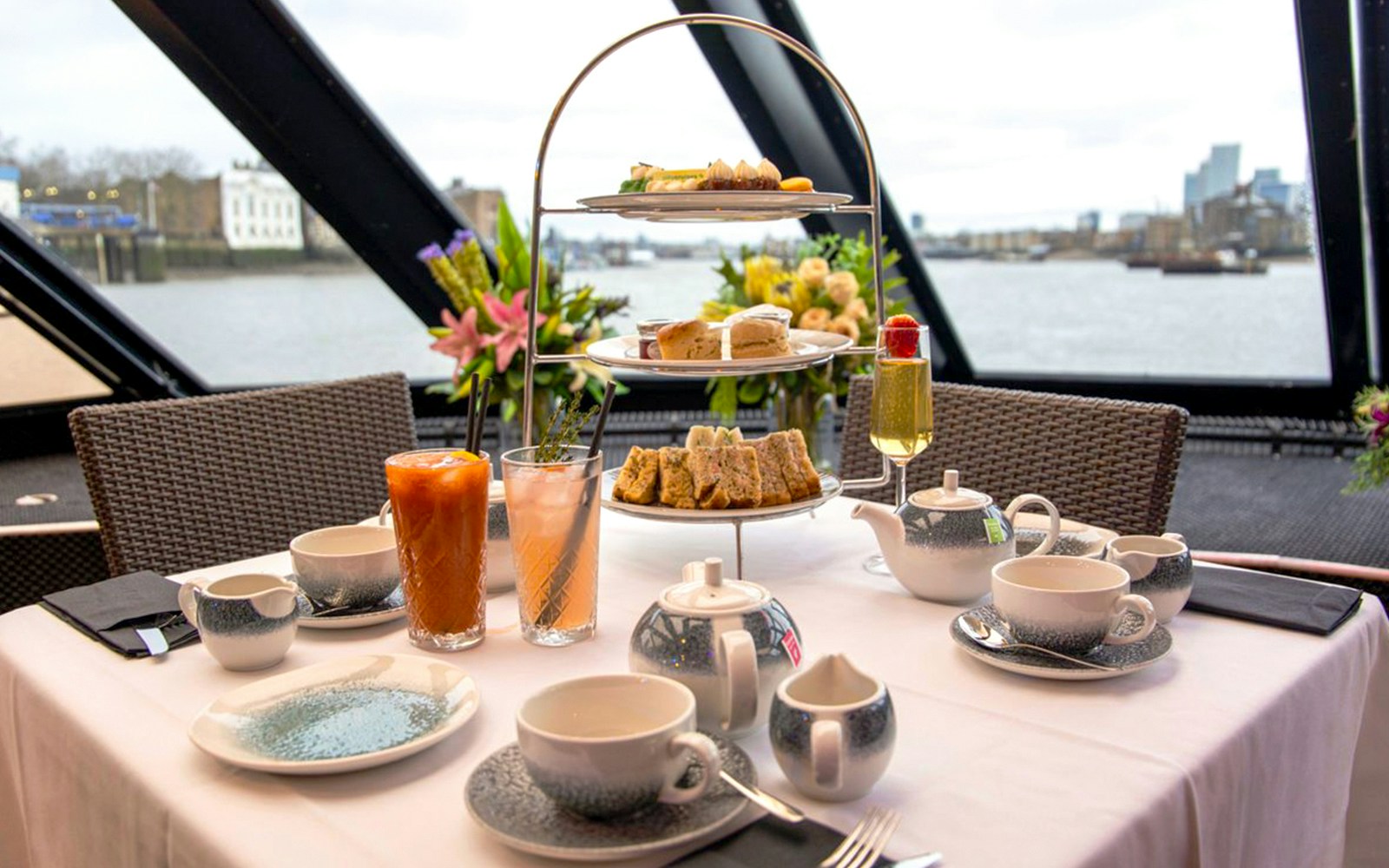 Afternoon tea setup with tiered tray and drinks on Thames cruise.