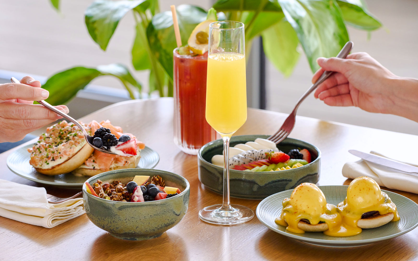 Brunch spread with eggs benedict, fruit bowls, and mimosas at Aura sky pool.
