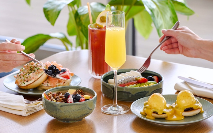 Brunch spread with eggs benedict, fruit bowls, and mimosas at Aura sky pool.