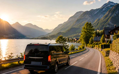 Van driving along a lakeside road with mountains near Hallstatt, Austria.