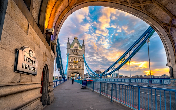 Tower Bridge in London at sunset, viewed from under an archway.