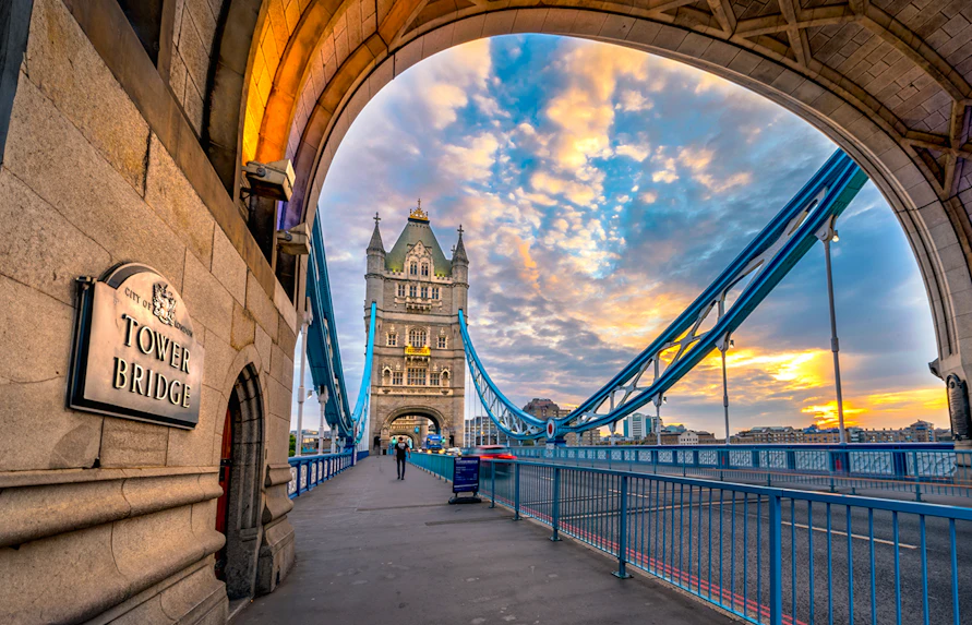 Tower Bridge in London at sunset, viewed from under an archway.