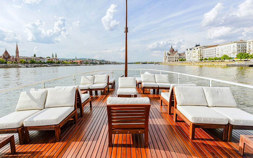 Outer deck seating area on Elegant Premium Sightseeing Cruise with cityscape views.