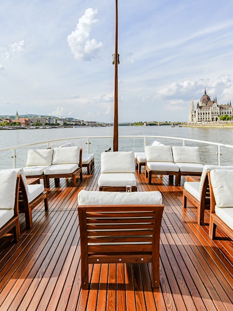 Outer deck seating area on Elegant Premium Sightseeing Cruise with cityscape views.