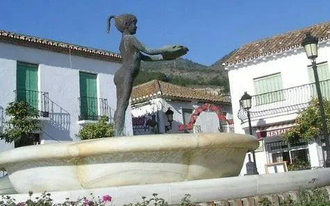 Benalmádena Pueblo fountain with statue in a quaint village square, part of self-guided city exploration game.