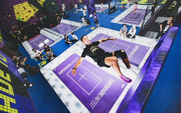 Woman jumping on trampoline at SuperPark Singapore indoor activity center.