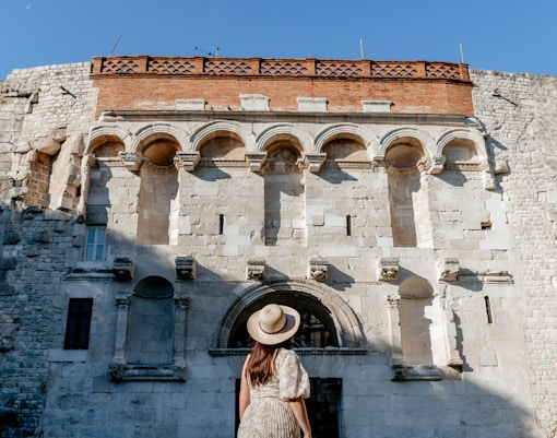 Entrance to Diocletian's Palace in Split, Croatia with tourists exploring the ancient stone archway.