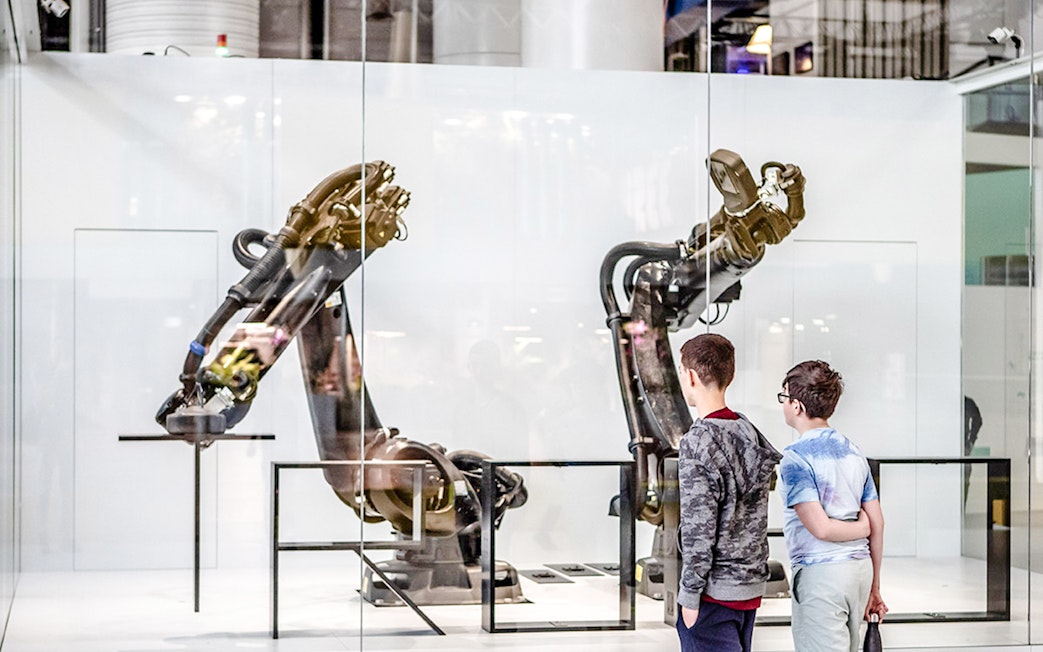 Children observing robotic arms exhibit at Science & Industry Museum, Paris, France.