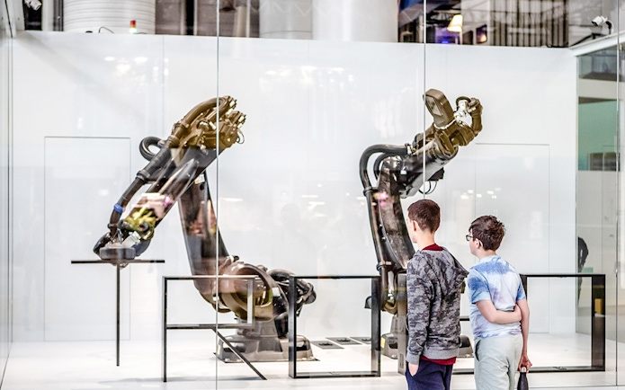 Children observing robotic arms exhibit at Science & Industry Museum, Paris, France.
