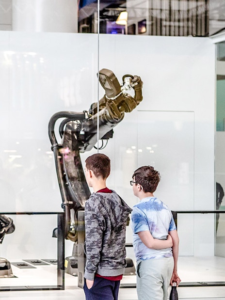 Children observing robotic arms exhibit at Science & Industry Museum, Paris, France.