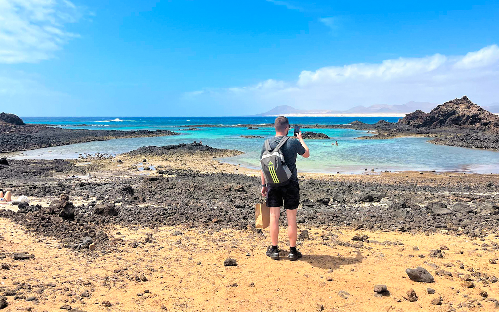 Tourist photographing rocky beach on Lobos Island half-day trip.