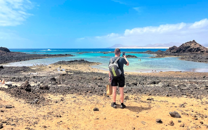 Tourist photographing rocky beach on Lobos Island half-day trip.