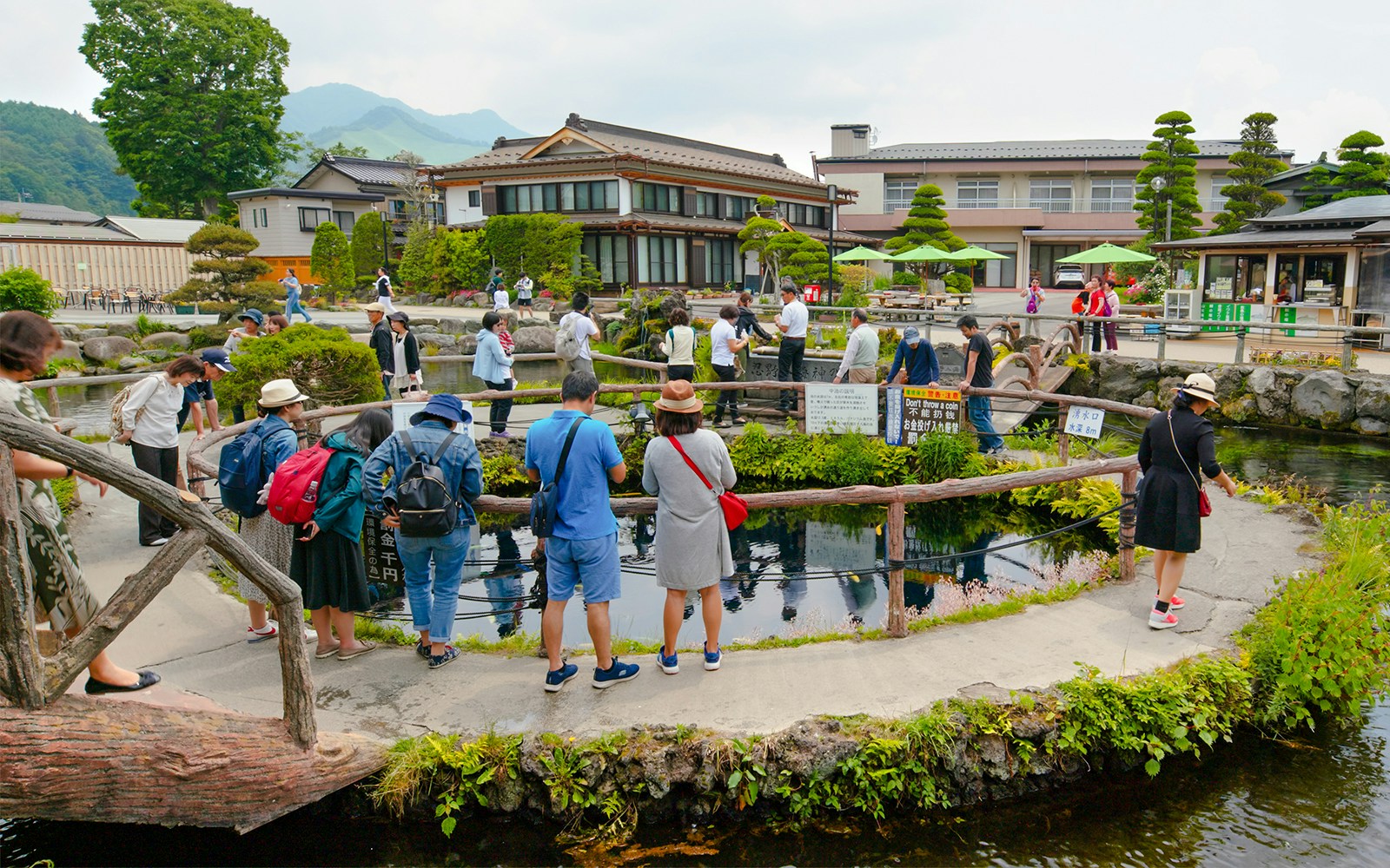 Visitors exploring ponds and traditional buildings at Oshino Hakkai Village, Japan.