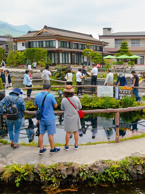 Visitors exploring ponds and traditional buildings at Oshino Hakkai Village, Japan.