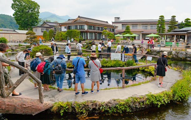 Visitors exploring ponds and traditional buildings at Oshino Hakkai Village, Japan.