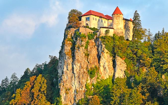 Bled Castle perched on a cliff surrounded by trees in Slovenia.