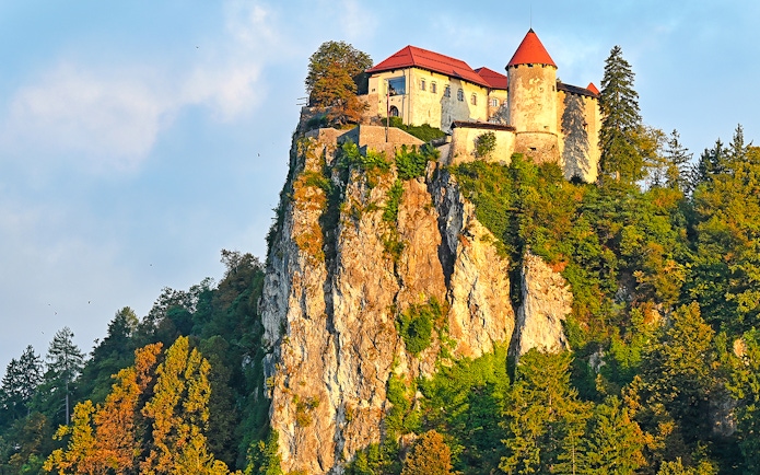 Bled Castle perched on a cliff surrounded by trees in Slovenia.