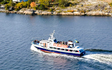 Boat cruising through Stockholm Archipelago with passengers on deck.
