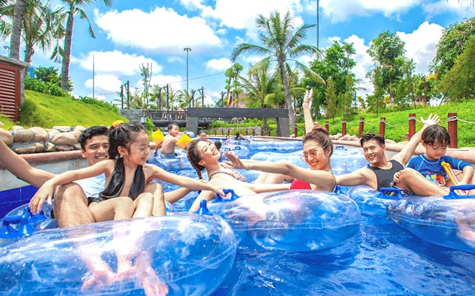 Visitors enjoying a lazy river ride at Sun World Halong, surrounded by palm trees.
