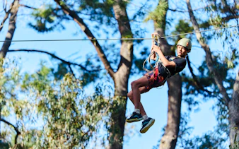 Participant ziplining at Busselton Forest Adventures High Ropes Course.