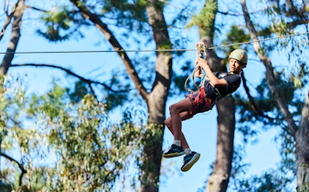 Participant ziplining at Busselton Forest Adventures High Ropes Course.
