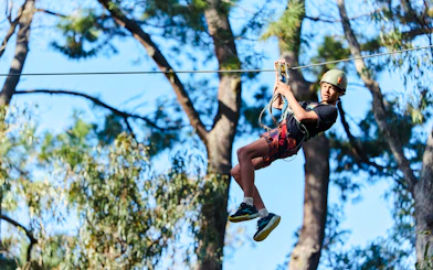 Participant ziplining at Busselton Forest Adventures High Ropes Course.