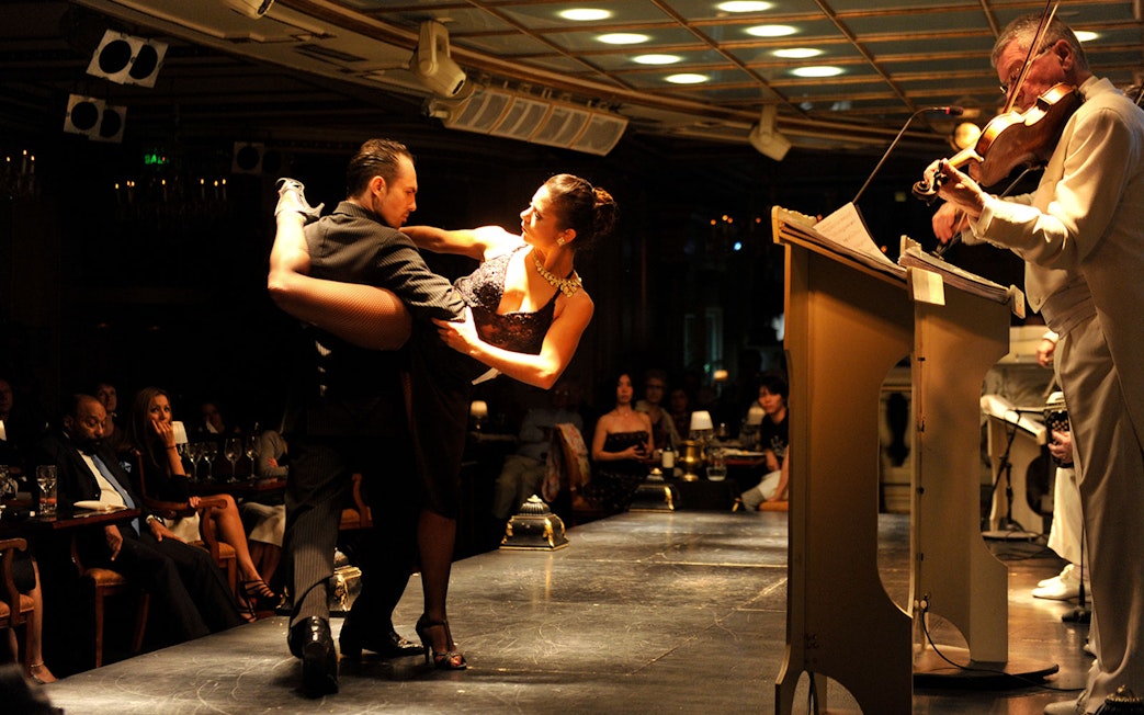 Dancers performing at Gala Tango Show with live violinist in Buenos Aires.