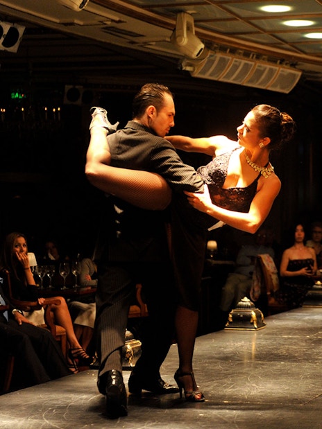 Dancers performing at Gala Tango Show with live violinist in Buenos Aires.