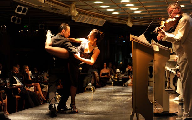 Dancers performing at Gala Tango Show with live violinist in Buenos Aires.