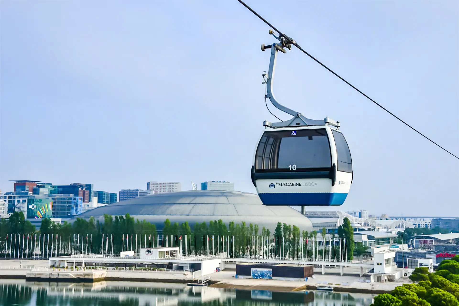 Lisbon cable car over waterfront with cityscape in background.